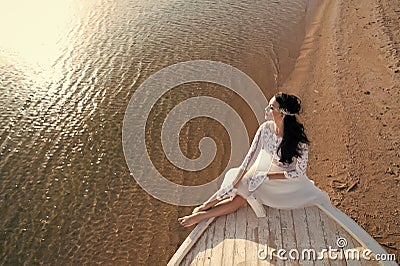 Bride adorable white wedding dress sunny day sit on boat or ship. Honeymoon sea beach. Things consider for wedding Stock Photo