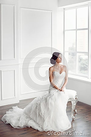 Bride in beautiful dress sitting on chair indoors Stock Photo