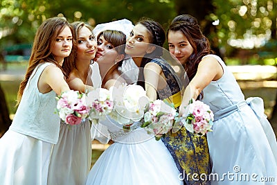 Bride and bridesmaids reach hands with bouquets to the cameraman Stock Photo
