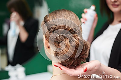 Bride getting ready for wedding. Professional hairdresser making coiffure for female client, applying hairspray in front of big Stock Photo