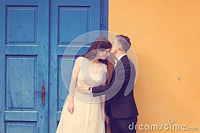 Bride and groom against yellow wall and blue door Stock Photo