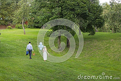Bride and groom with blue balloons and picnic basket near apple trees Editorial Stock Photo