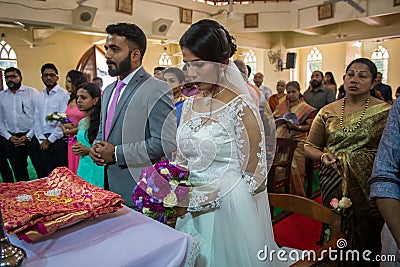 Bride, groom, family, and friends attending the Catholic wedding ceremony. Religious celebration at church in Kerala province in Editorial Stock Photo