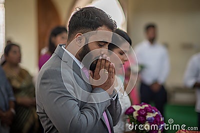 Bride, groom, family, and friends attending the Catholic wedding ceremony. Religious celebration at church in Kerala province in Editorial Stock Photo