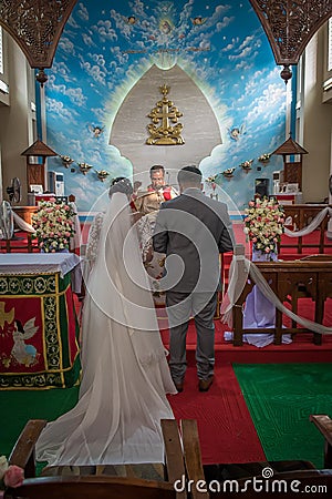 Bride, groom, family, and friends attending the Catholic wedding ceremony. Religious celebration at church in Kerala province in Editorial Stock Photo