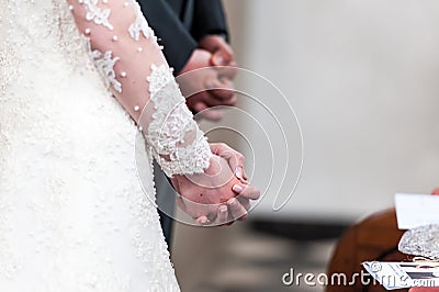 Bride and groom folding hands in church Stock Photo