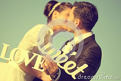 Bride and groom having fun and posing with Sweet Love letters in sunlight Stock Photo