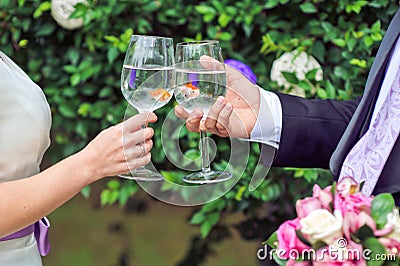 Bride and groom holding glasses with goldfish Stock Photo