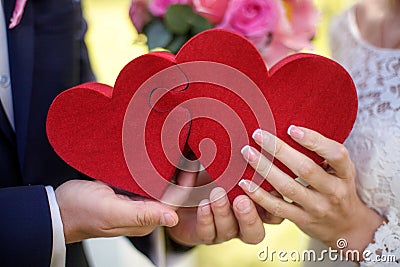 Bride and groom holding red puzzle hearts, wedding concept, closeup Stock Photo