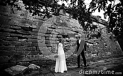 Bride and groom look gorgeous standing behind an old wall of a c Stock Photo