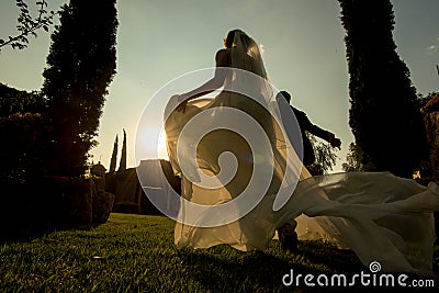 Bride and groom running away at sunset, garden wedding at sunset, hacienda wedding in Mexico Stock Photo