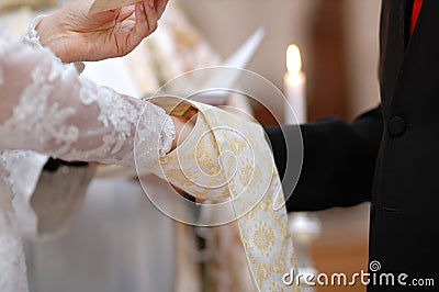 Bride and groom's hands and priest's cassock Stock Photo