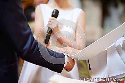 Bride and groom's hands wrapped in priest's cassock Stock Photo