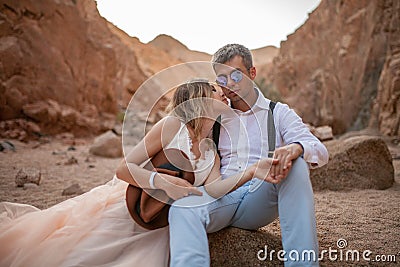 Bride and groom sit and hold hands in canyon. Closeup. Stock Photo
