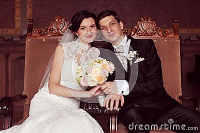 Bride and groom sitting on royal chairs Stock Photo