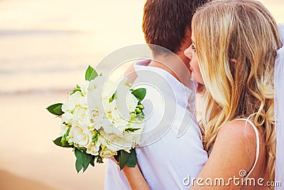 Bride holding bouquet of white flowers gazing at the ocean into Stock Photo