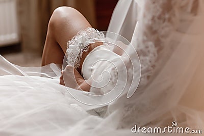 The bride holds in hand lose-up garter in hotel room. morning preparation wedding concept Stock Photo