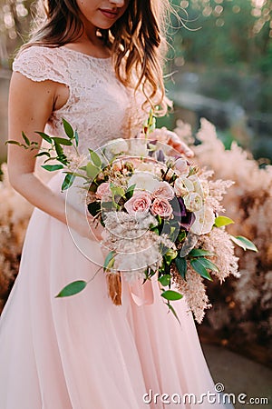 A bride holds rustic wedding bouquet consisting of different flowers. Decoration Artwork Stock Photo