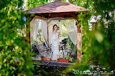 bride with long curls with bouquet of lilies kalla in a gazebo in a summer park Stock Photo