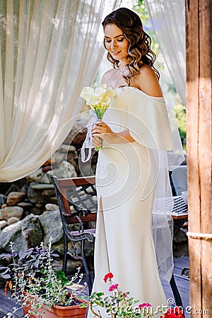 bride with long curls with bouquet of lilies kalla in a gazebo in a summer park Stock Photo