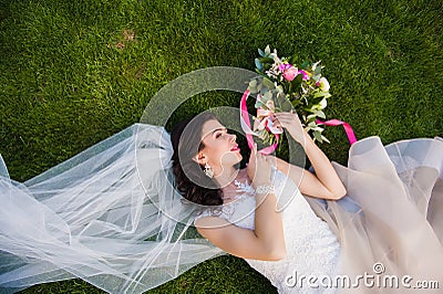 Bride lying in the grass with wedding bouquet Stock Photo