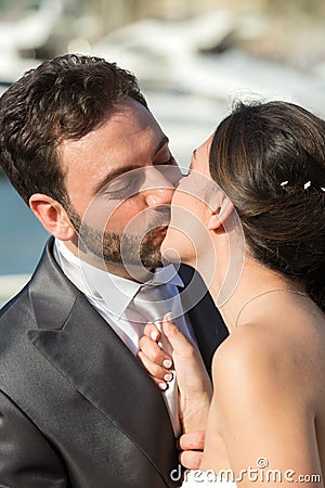 Bride pulls the tie of the groom while kissing him. Stock Photo