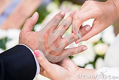 Bride putting ring on groom finger Stock Photo