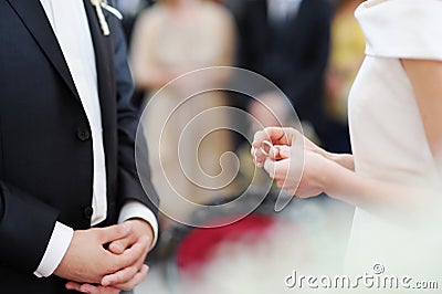Bride putting a ring on groom's finger Stock Photo