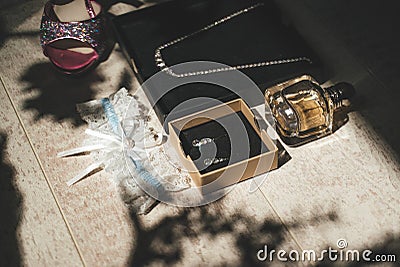 Bride`s accessories: shoes, earrings, jewelry, perfume and garter on wooden background. Wedding day concept. Stock Photo