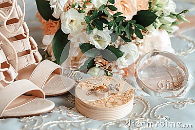 Bride`s bouquet, beige shoes, wedding rings and perfume. The bride`s accessories Stock Photo