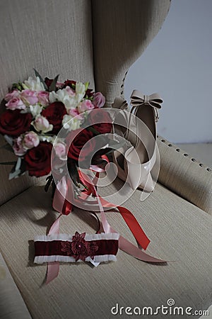 A bride`s bouquet of red and pink roses, women`s shoes, a garter of the bride Stock Photo