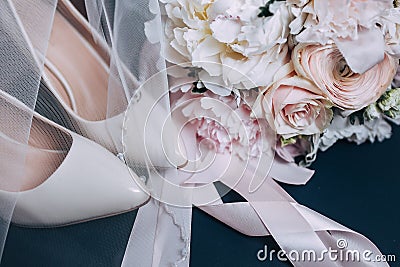 Bride`s shoes and a bouquet of peonies close-up. Gentle color and veil Stock Photo