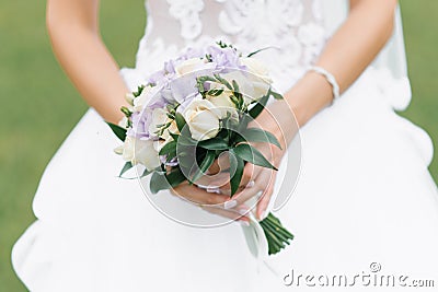 The bride`s wedding bouquet of milk roses and lilac eustoms in the hands of the bride Stock Photo