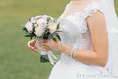 The bride`s wedding bouquet of milk roses and lilac eustoms in the hands of the bride close-up Stock Photo