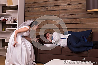 Bride is shouting on sleeping on couch groom Stock Photo