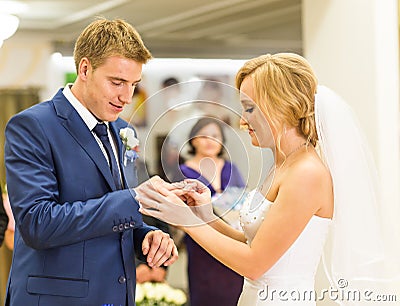 Bride slipping ring on finger of groom at wedding Stock Photo