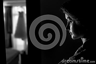 Bride stands thoughtfully in the dark room Stock Photo