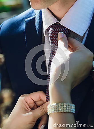 Bride straightens to groom his tie, close-up of hands Stock Photo