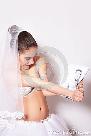 Bride in a veil, underwear and skirt tears the photo of her groom Stock Photo