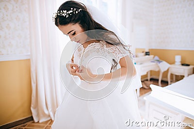 The bride wears a wedding dress in bedroom. Last preparations for the wedding. Wedding morning Stock Photo