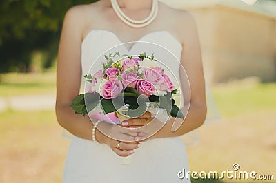 Bride after the wedding ceremony in the sun park holds a beautiful bouquet Stock Photo