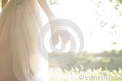 Bride in wedding dress holds shoes against sun. fine art photography Stock Photo