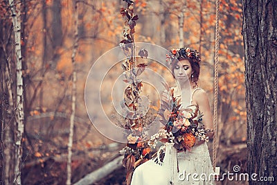 The bride on a wedding walk on a decorative swing, golden autumn Stock Photo