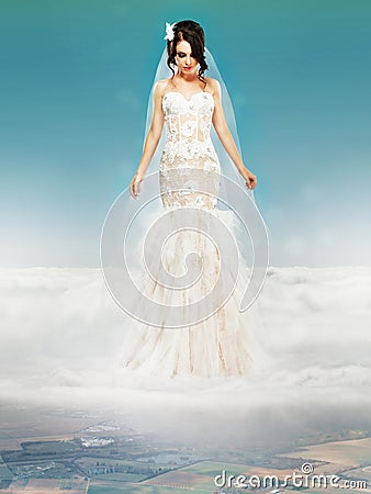 Bride in Wedding White Dress standing on a Cloud Stock Photo