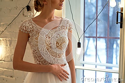 The bride in a white lace dress with embroidered bodice, indoors in loft style.High key. Stock Photo