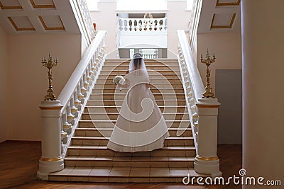 Bride in white wedding dress climbs the stairs in the theater Stock Photo