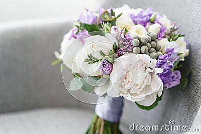 Brides wedding bouquet with peonies, freesia and other flowers on black arm chair. Light and lilac spring color. Morning Stock Photo