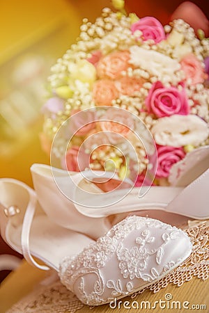 Brides wedding shoes with a bouquet with roses and other flowers. Stock Photo