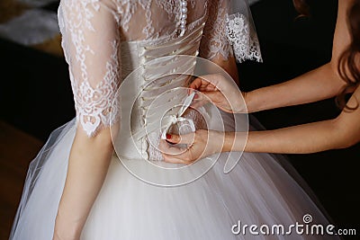 Bridesmaid is helping the bride to dress. Stock Photo