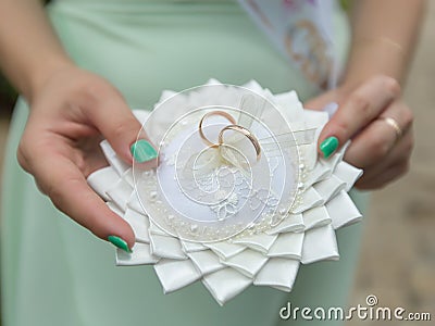 Bridesmaid holds ring pillow with pair golden wedding rings Stock Photo